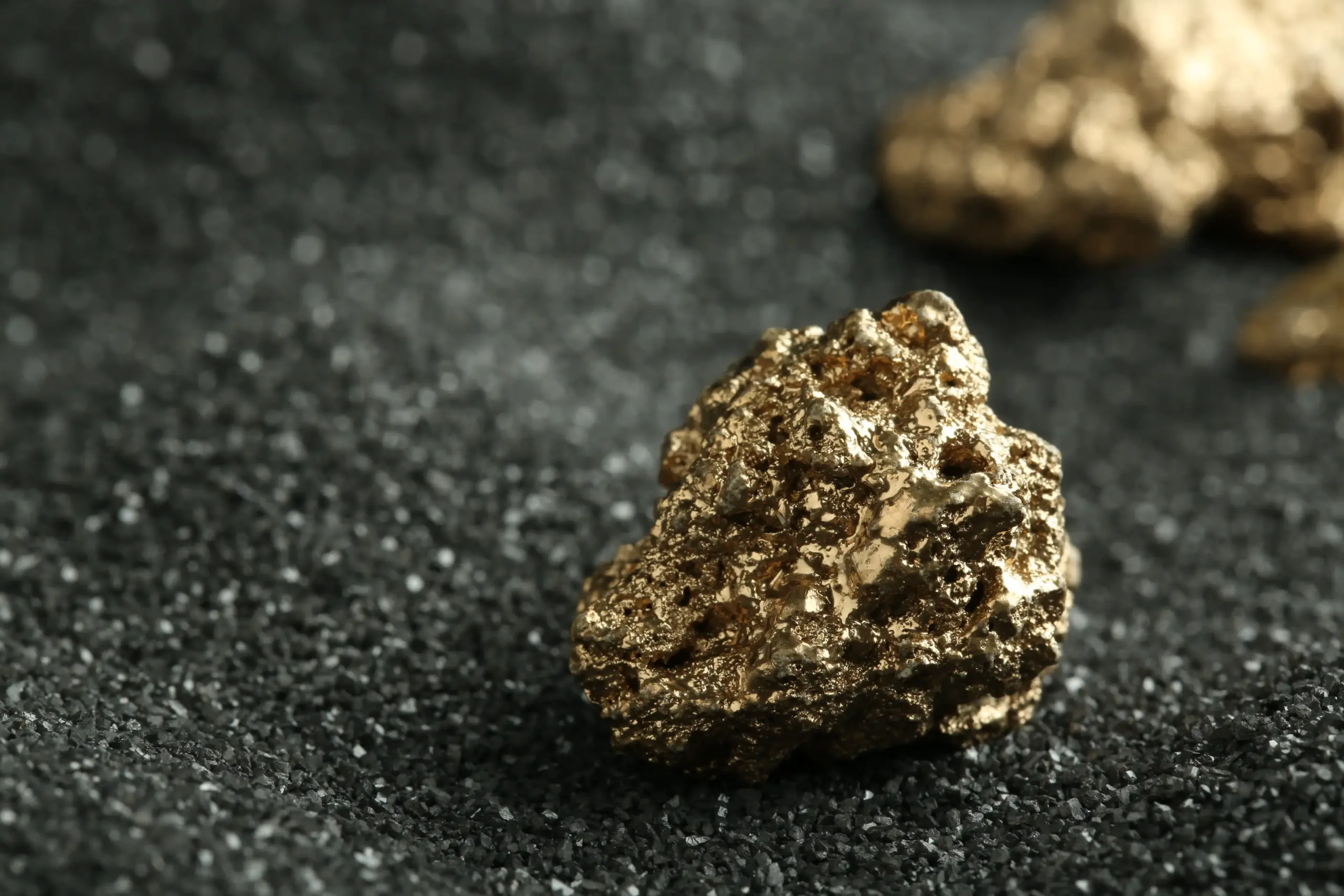 close up of gold nuggets on gray sand 2026 04 08 16 47 47 utc scaled 1